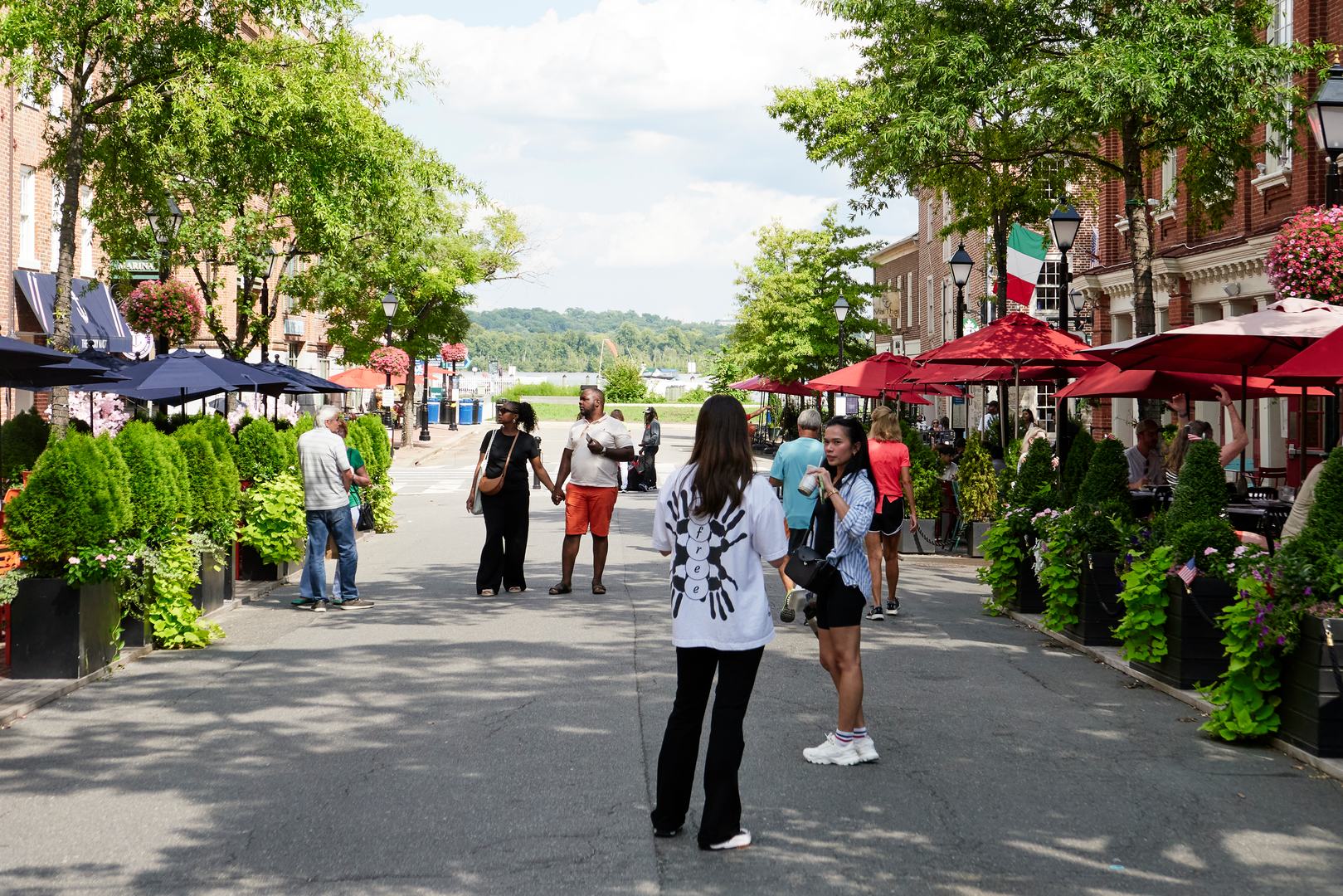 A diverse mix of residents and tourists stroll the pedestrian-only zone and sit at tables outside