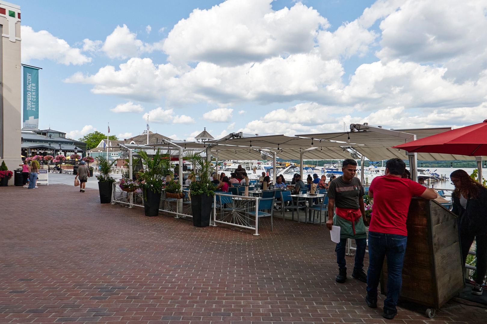 A diverse mix of residents and tourists eat and stroll at the waterfront