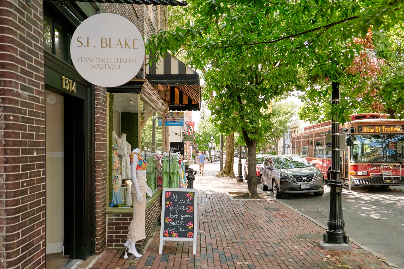 A street scene with the King Street trolley driving past a luxury boutique